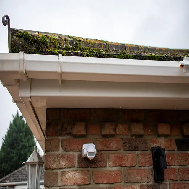The final result of a professional fascia and gutter wash on a brick house, showing bright white, moss-free uPVC surfaces.