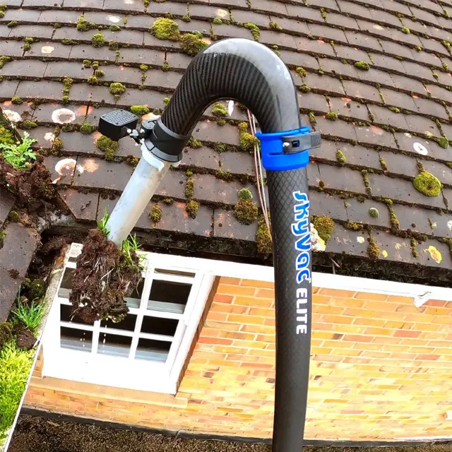 High-reach gutter cleaning system clearing a blocked gutter without the need for ladders, provided by Crystal Clean Windows.