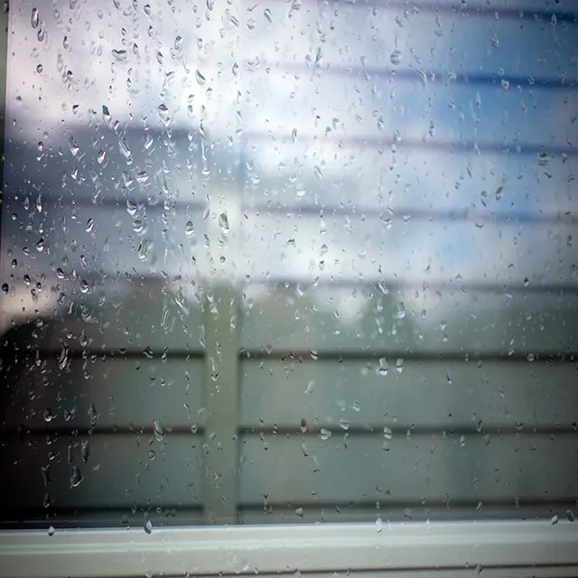 Raindrops on a clean window pane, illustrating that professional pure water cleaning remains effective even in rainy UK weather.